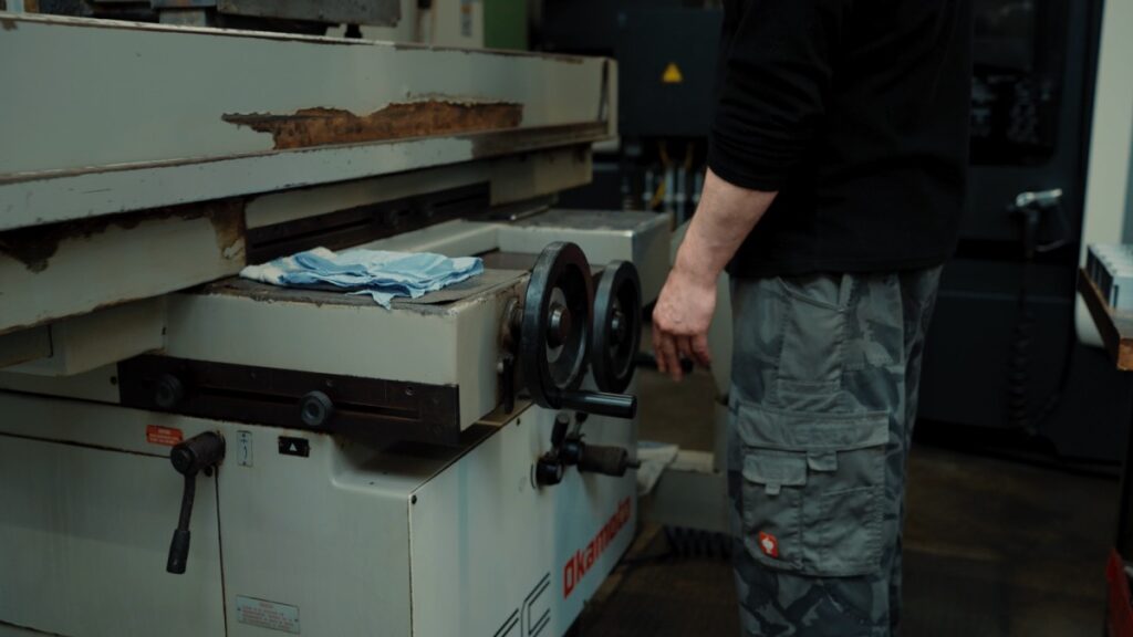 Arbeiter bedient das Handrad einer Präzisionsschleifmaschine